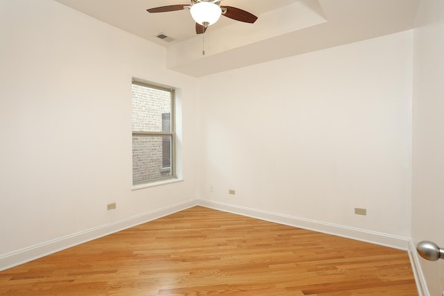 unfurnished room featuring light wood finished floors, visible vents, ceiling fan, and baseboards