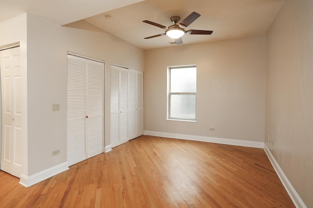 unfurnished bedroom featuring light wood-type flooring, baseboards, and two closets