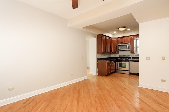 kitchen with stainless steel appliances, baseboards, dark countertops, and light wood-style flooring