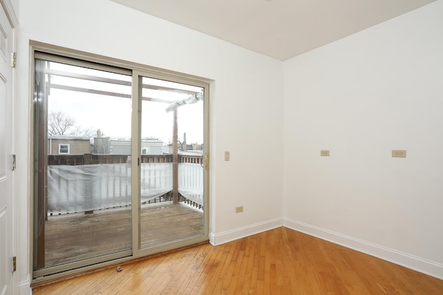 spare room featuring a healthy amount of sunlight, baseboards, and light wood-style floors