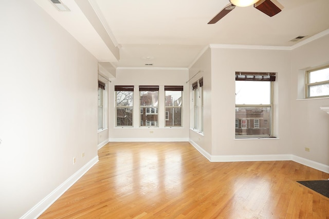 spare room with baseboards, visible vents, light wood finished floors, and ornamental molding