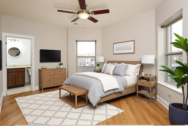 bedroom with visible vents, baseboards, ensuite bath, and light wood-style flooring