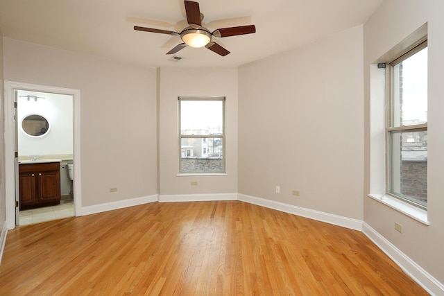 spare room with a ceiling fan, light wood-type flooring, baseboards, and a sink