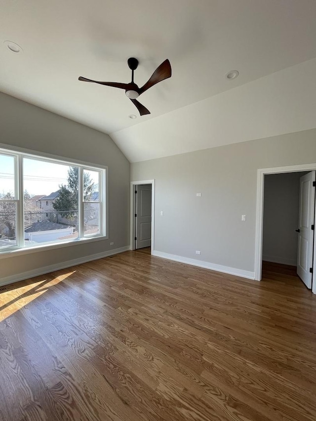 spare room featuring ceiling fan, baseboards, wood finished floors, and vaulted ceiling