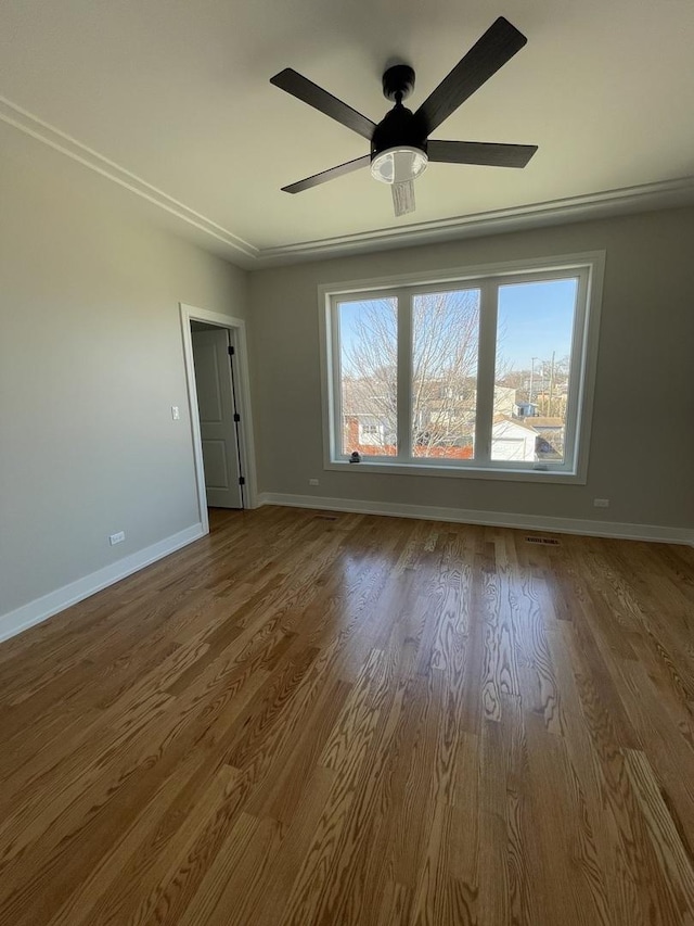 empty room with a ceiling fan, wood finished floors, and baseboards