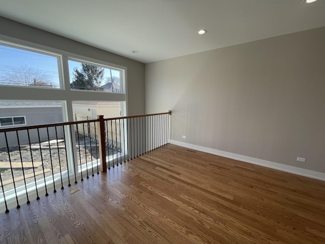 unfurnished room with recessed lighting, wood finished floors, and baseboards