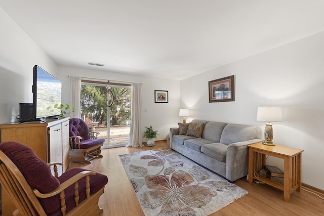 living area featuring light wood finished floors, visible vents, and baseboards