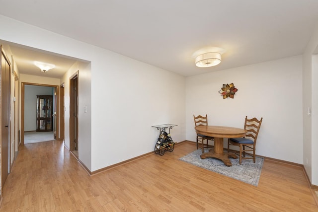 dining room featuring light wood finished floors and baseboards