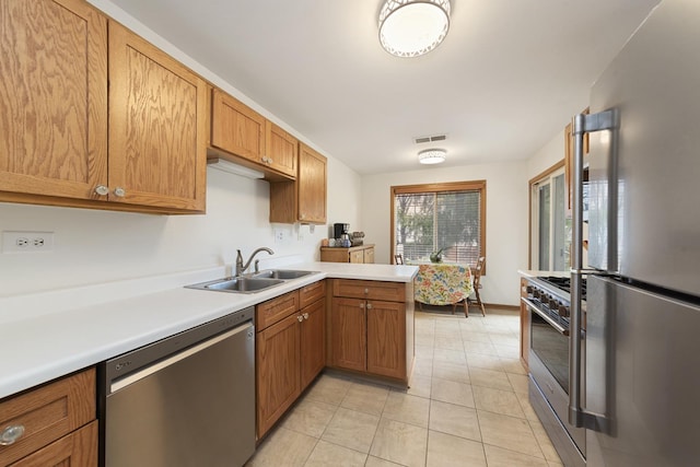 kitchen featuring visible vents, light countertops, a peninsula, stainless steel appliances, and a sink