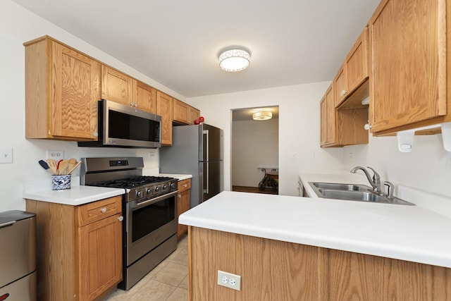 kitchen featuring light tile patterned floors, a peninsula, a sink, stainless steel appliances, and light countertops