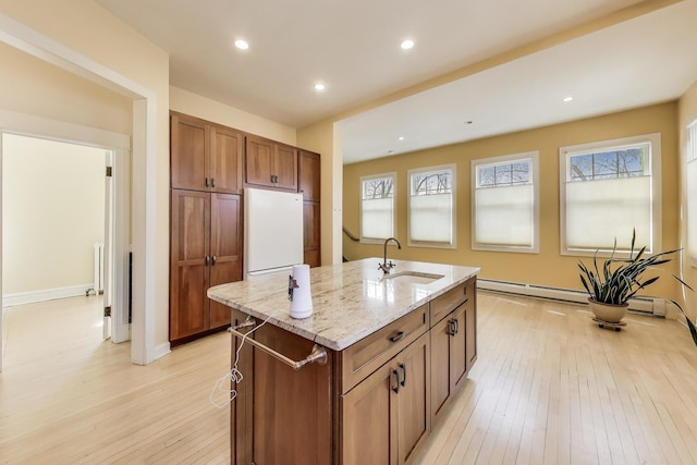 kitchen featuring light wood-style flooring, a sink, light stone counters, freestanding refrigerator, and baseboard heating