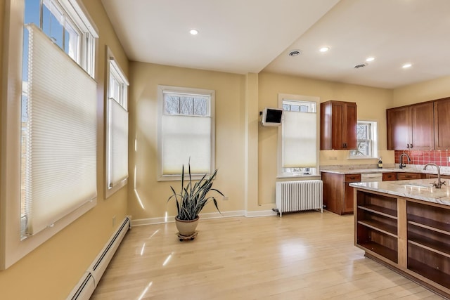 kitchen featuring light stone countertops, open shelves, radiator heating unit, a baseboard heating unit, and light wood-type flooring