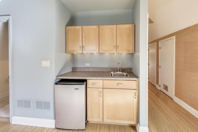 kitchen with visible vents, light brown cabinets, light countertops, fridge, and a sink