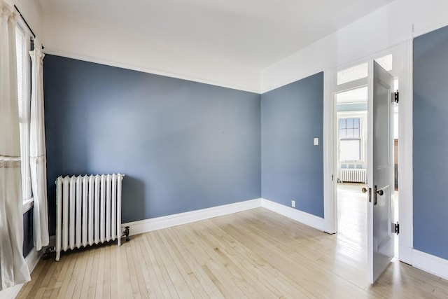 empty room with wood-type flooring and radiator heating unit