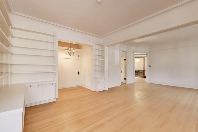 spare room featuring an inviting chandelier, crown molding, and light wood-style floors