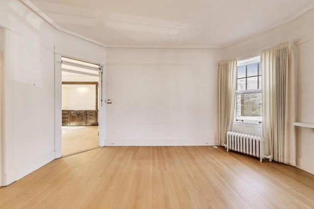 empty room featuring light wood finished floors, radiator, baseboards, and ornamental molding