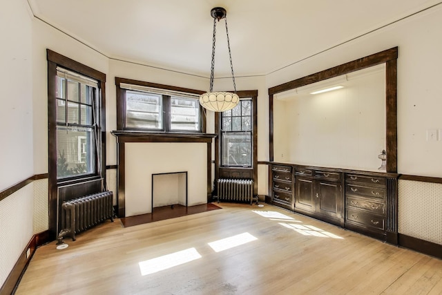 interior space with a wainscoted wall, radiator, wallpapered walls, and wood finished floors