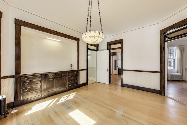 unfurnished room with wainscoting, radiator, and light wood-style floors