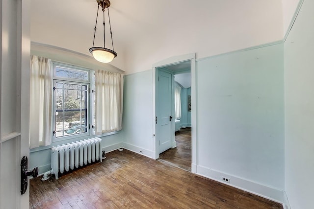 unfurnished dining area featuring baseboards, wood-type flooring, and radiator heating unit