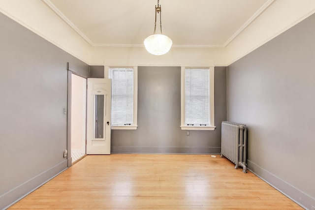 unfurnished room featuring baseboards, crown molding, radiator heating unit, and light wood finished floors