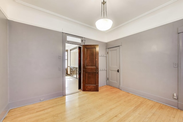 spare room featuring hardwood / wood-style floors, crown molding, and baseboards