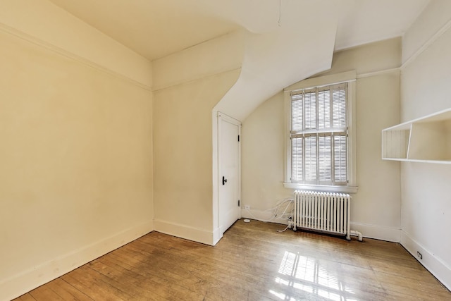 additional living space featuring baseboards, radiator, and hardwood / wood-style flooring