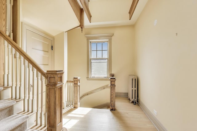 stairway featuring radiator heating unit, baseboards, and wood-type flooring