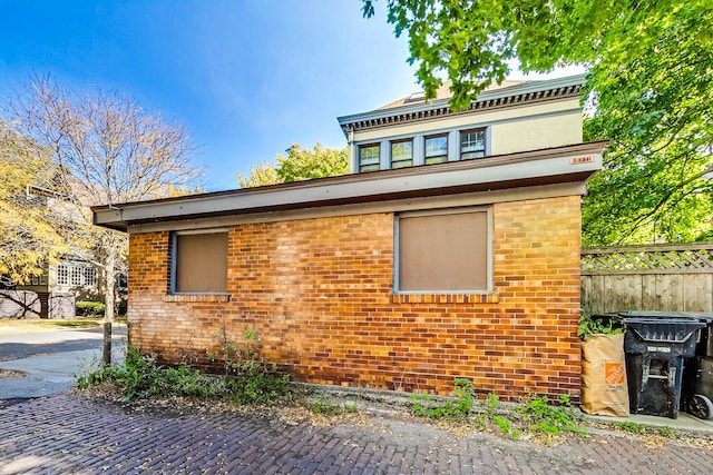 view of side of home featuring brick siding and fence