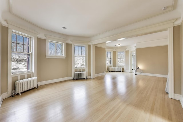 empty room with baseboards, radiator, and light wood-style flooring