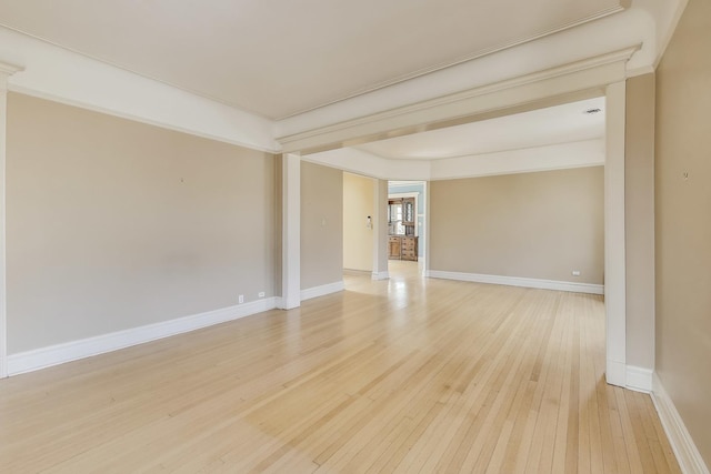 spare room with baseboards and light wood-type flooring