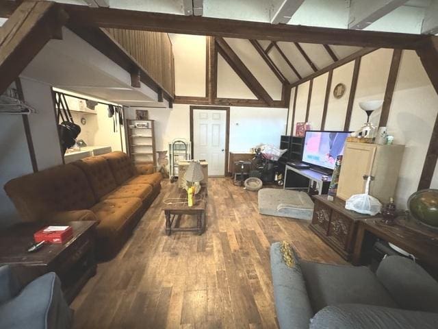 living area featuring beamed ceiling, high vaulted ceiling, and wood finished floors