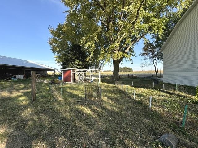 view of yard with a rural view, an outdoor structure, and fence