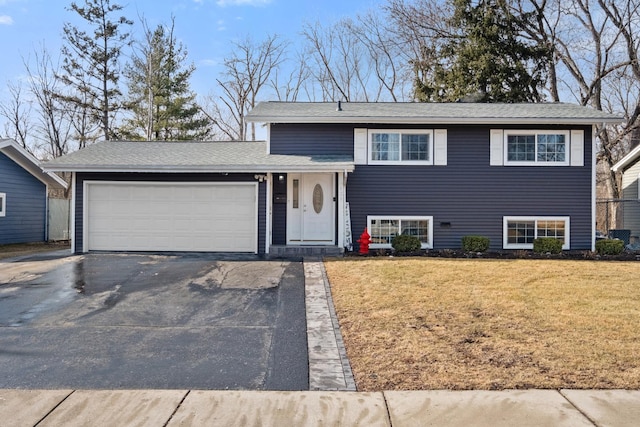 tri-level home with aphalt driveway, an attached garage, and a front yard