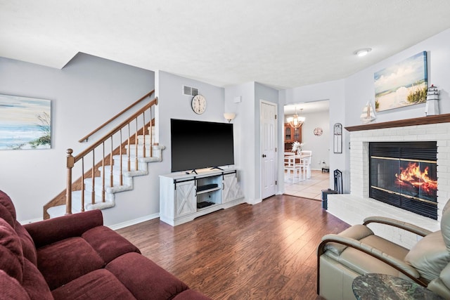 living area with visible vents, baseboards, stairway, a fireplace, and wood finished floors