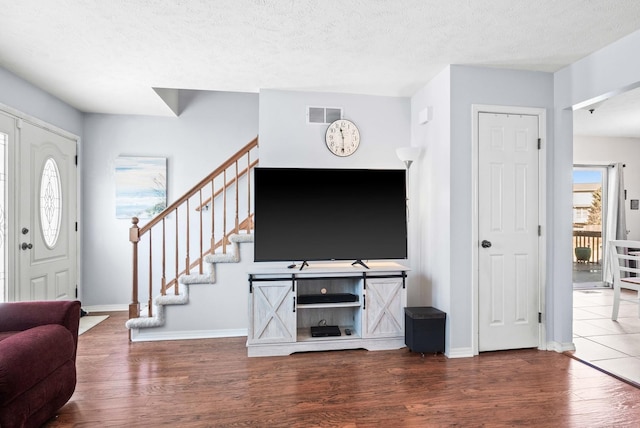 living room with visible vents, a textured ceiling, wood finished floors, and stairs