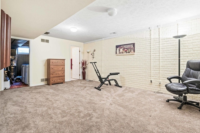 exercise area with visible vents, a textured ceiling, brick wall, and carpet flooring