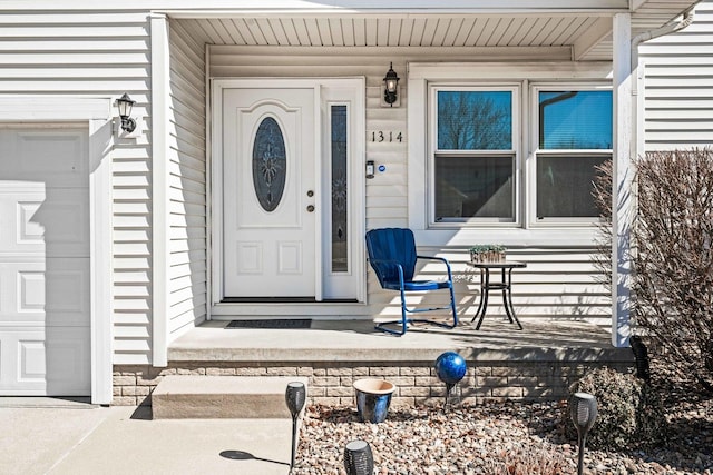 doorway to property with an attached garage and covered porch