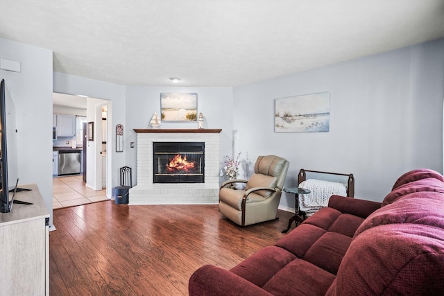 living area with a brick fireplace and wood finished floors