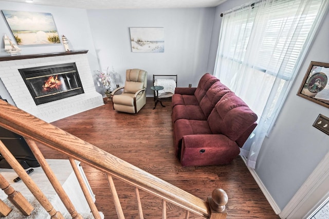 living area featuring baseboards, wood finished floors, and a fireplace