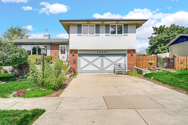 split level home featuring brick siding, driveway, a garage, and fence