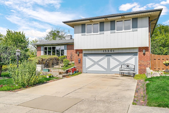 split level home featuring a garage, brick siding, and driveway