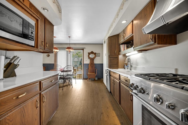 kitchen with dark wood finished floors, a sink, light countertops, high end stainless steel range, and exhaust hood