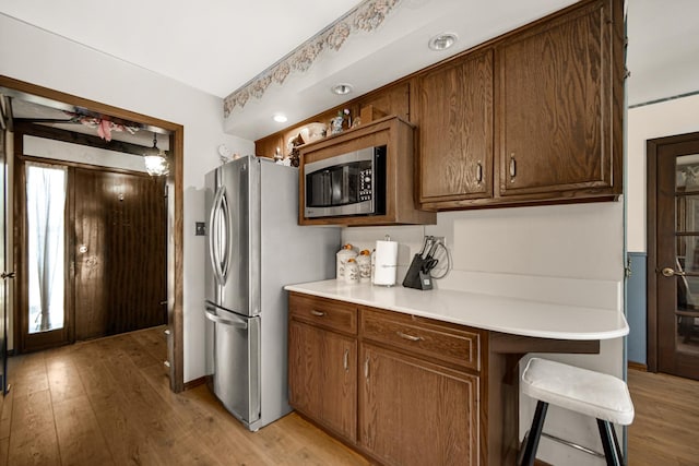 kitchen with light countertops, a kitchen breakfast bar, light wood-style floors, and stainless steel appliances