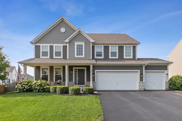 view of front of home with aphalt driveway, stone siding, a front yard, and fence