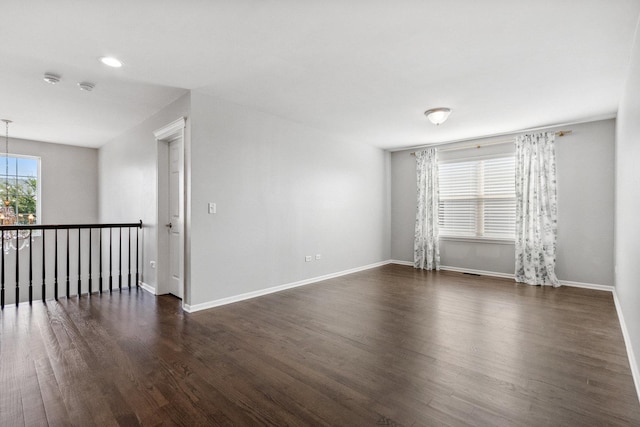 empty room featuring dark wood finished floors, a notable chandelier, recessed lighting, and baseboards