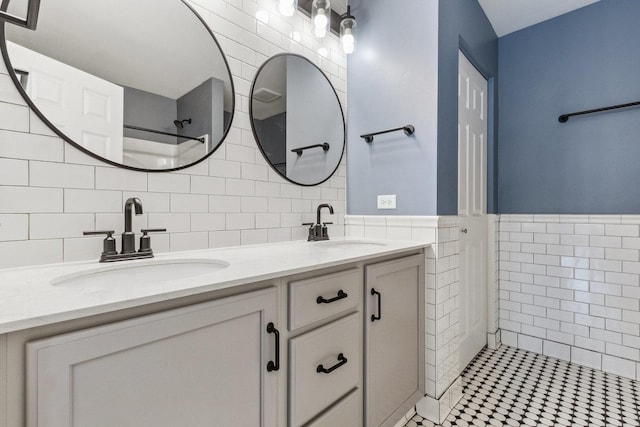 full bath featuring a sink, walk in shower, tile walls, and double vanity