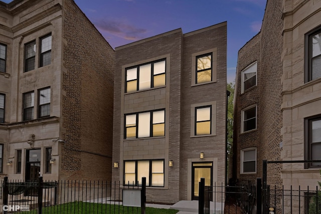 property at dusk with a fenced front yard