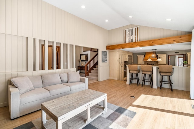 living area with recessed lighting, light wood-style flooring, high vaulted ceiling, and stairs