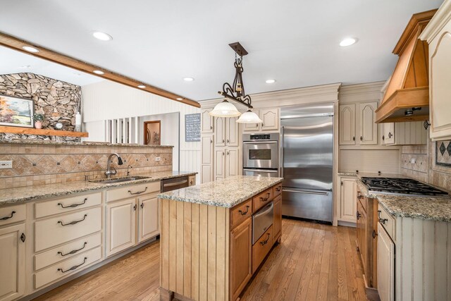 kitchen featuring a sink, a warming drawer, cream cabinets, and appliances with stainless steel finishes