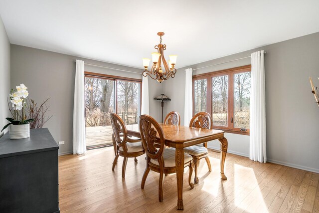 dining area featuring baseboards, light wood-style floors, and an inviting chandelier